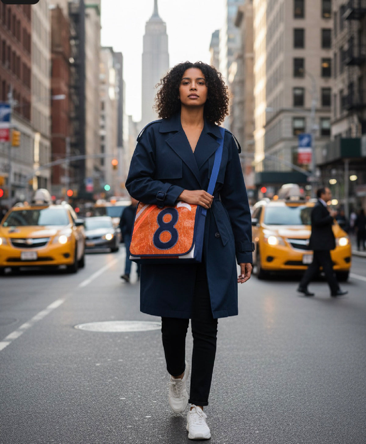 Frau mit Messenger Bag aus orangem Segeltuch mit der Zahl 8 auf einer Straße in New York. [KI]